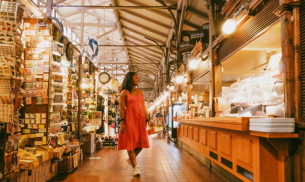 The lit timber aisle of Turku's historic market hall with delicatessen counters