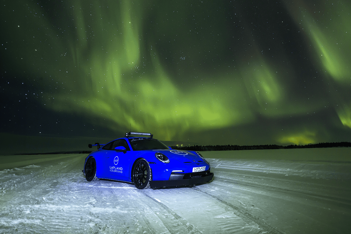 Blue sports car on a frozen-lake driving track under the northern lights