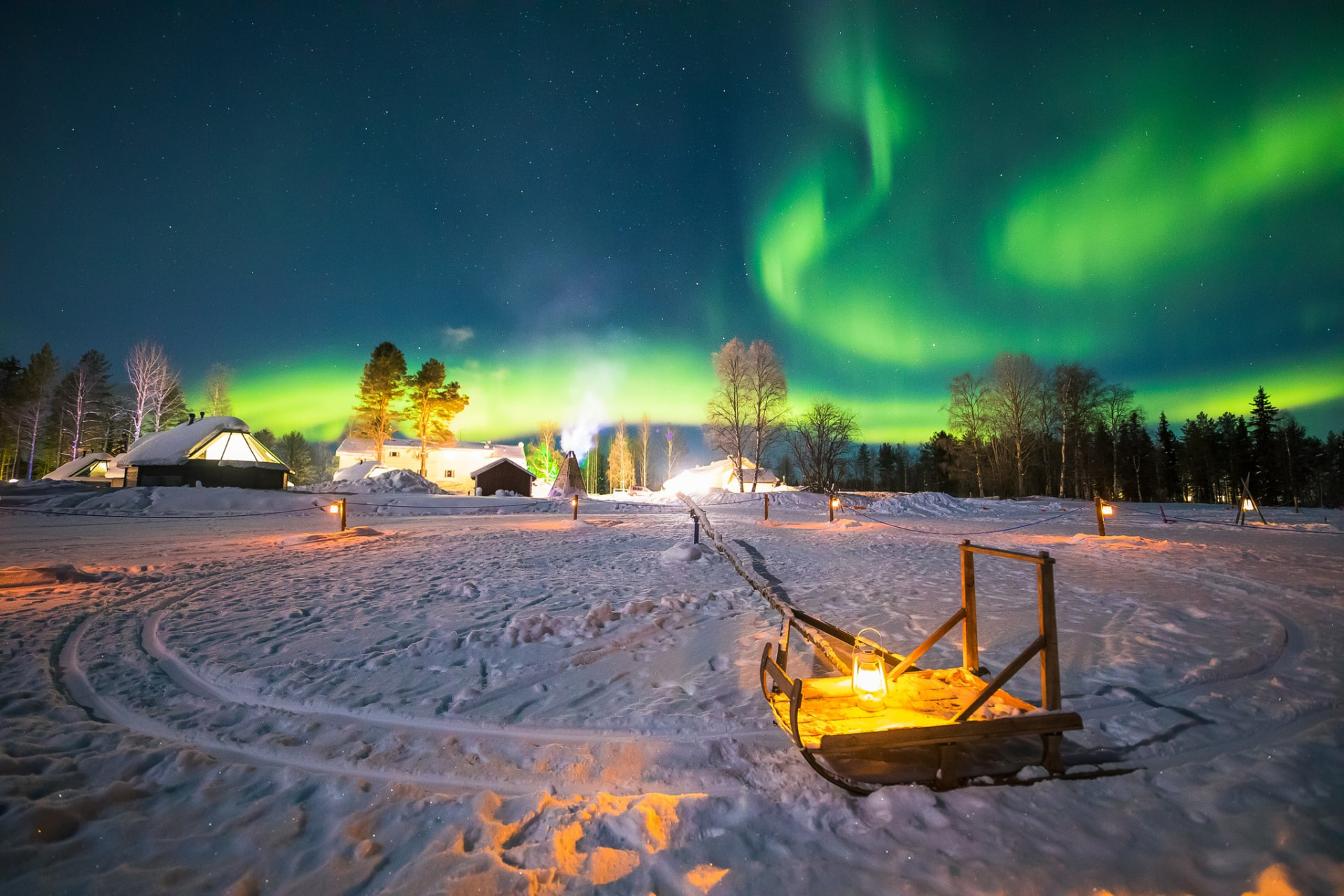 Lantern-lit sledge on snow at Apukka with auroras above the resort
