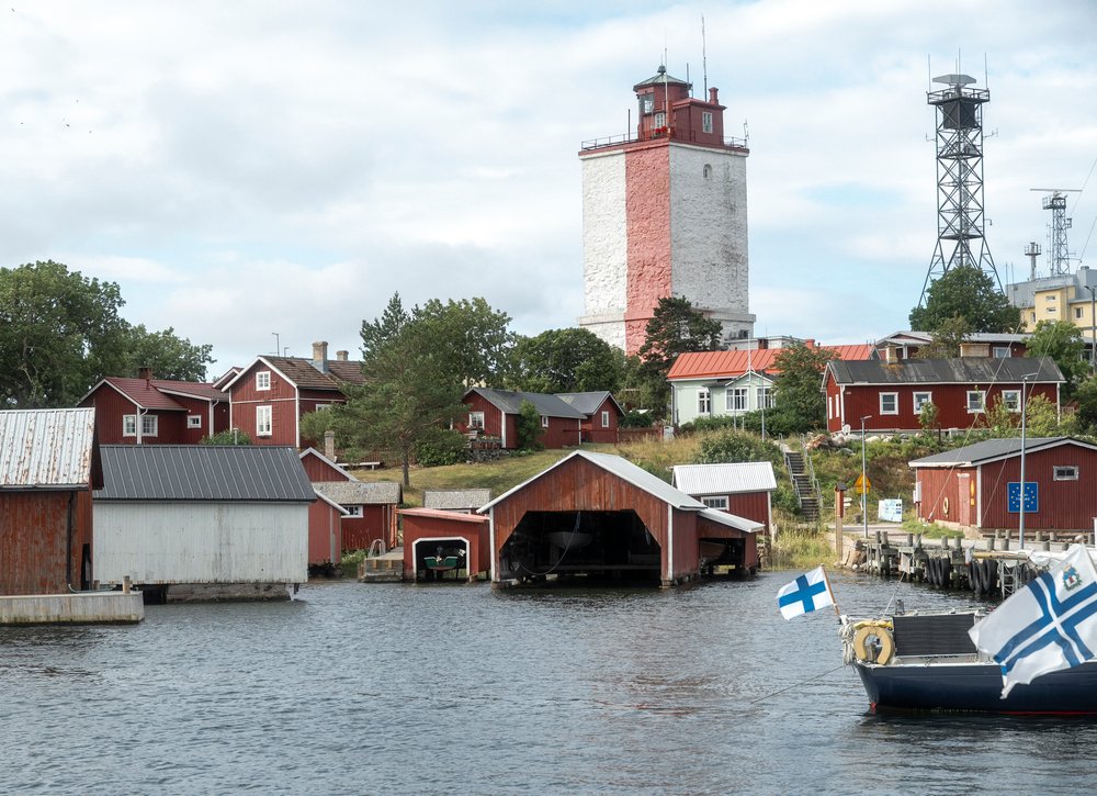 The red and white lighthouse above the boathouses of Utö island seen from the water
